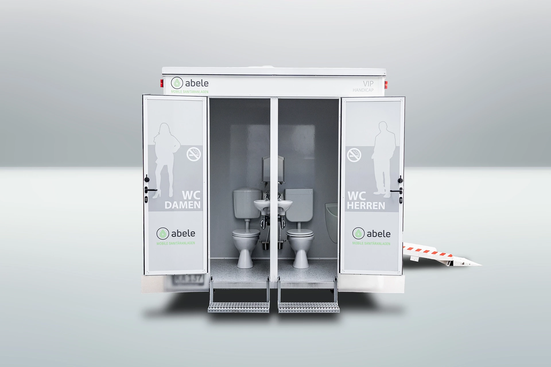 Toilettenwagen Modell Exklusiv – Handicap +2 8 Mobile Toilette mit zwei Kabinen, links für Damen, rechts für Herren, mit Rampe für Barrierefreiheit.