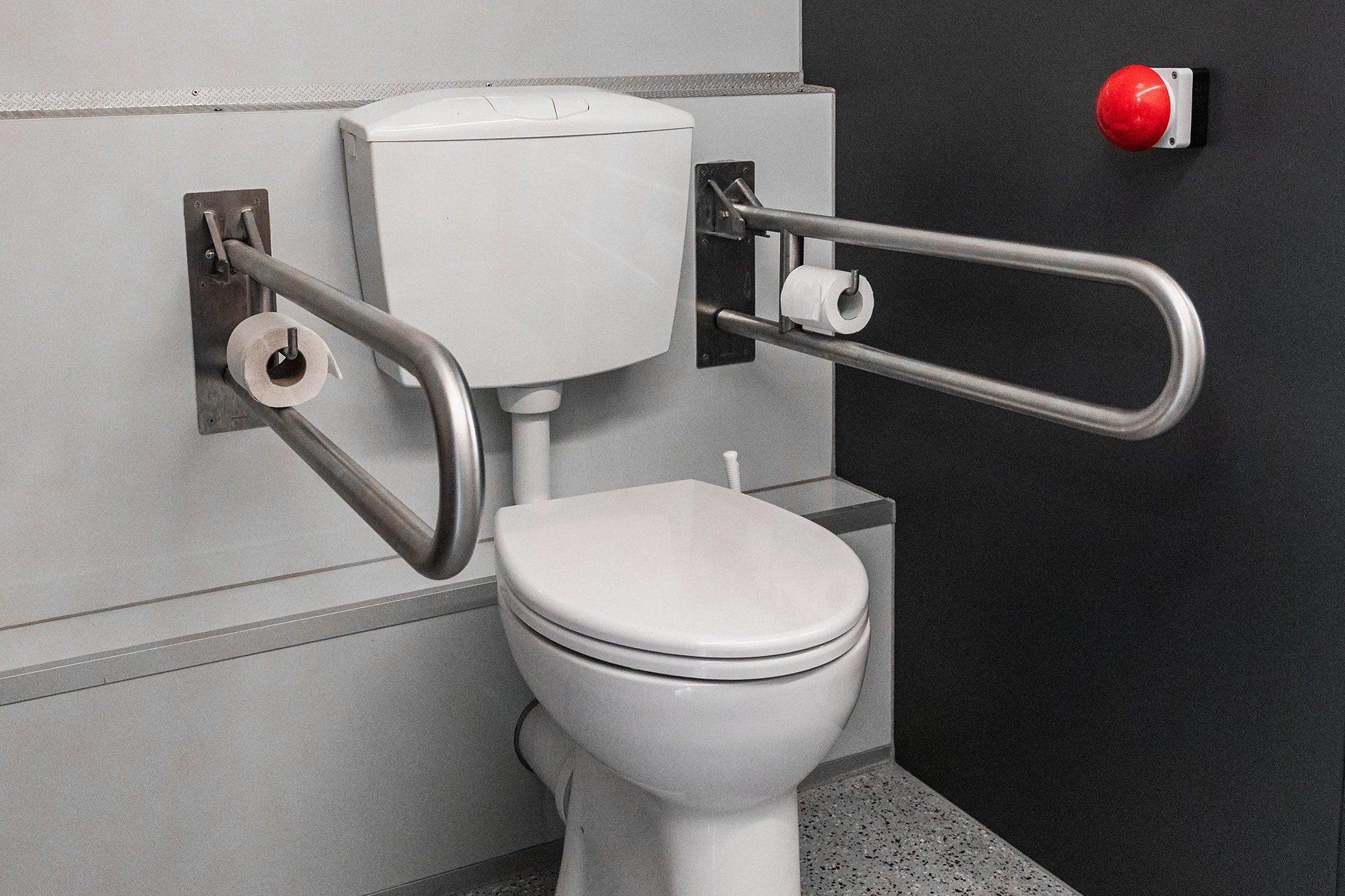 Toilettenwagen Modell Exklusiv – Handicap +2 7 Barrierefreie Toilette mit Haltegriffen, Notrufknopf und Toilettenpapierhalter zur Unterstützung von Menschen mit Behinderungen.