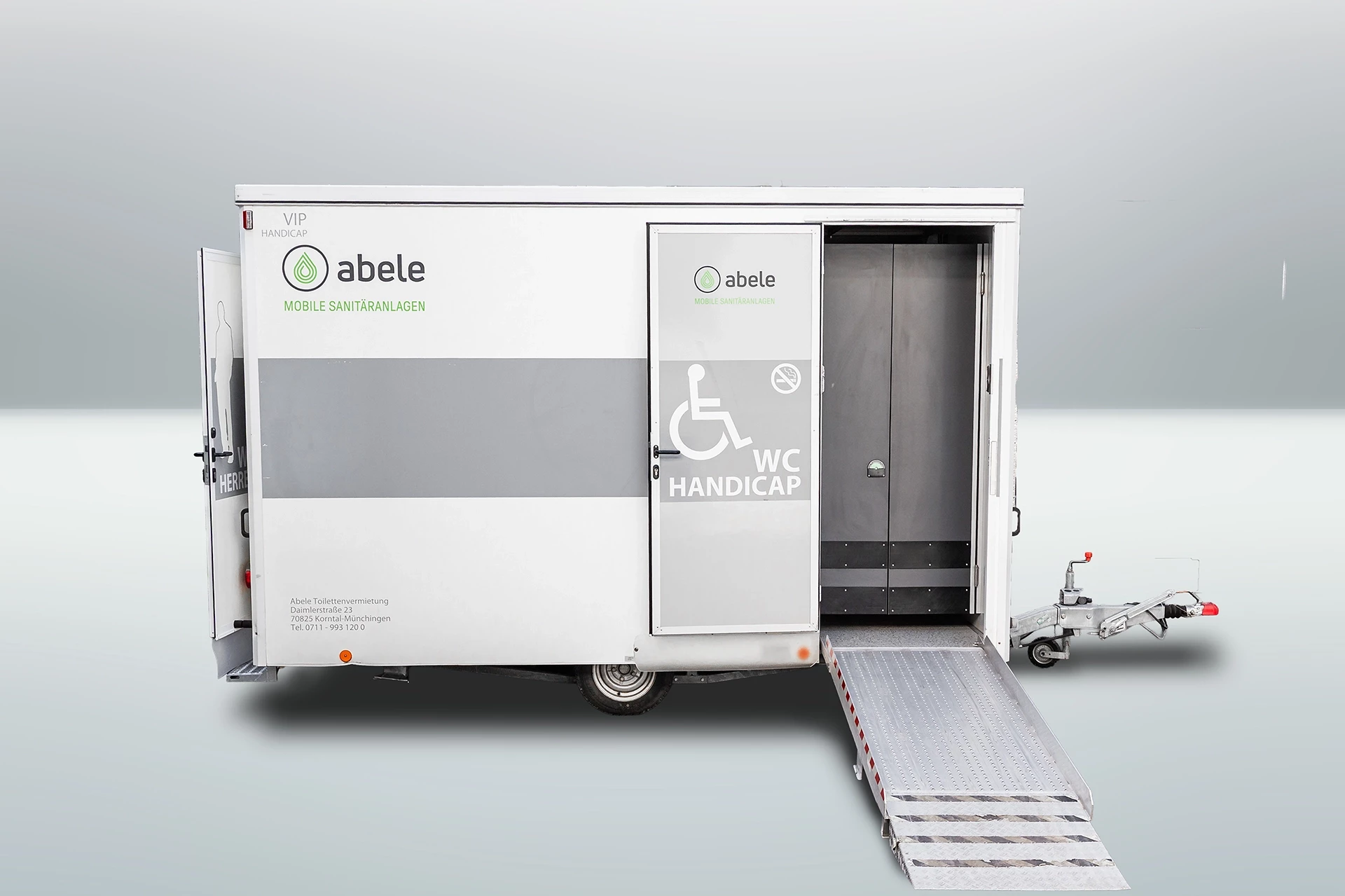 Toilettenwagen Modell Exklusiv – Handicap +2 3 Barrierefreies, mobiles WC mit Rollstuhlrampe und Handicap-Symbol, Tür teilweise geöffnet.